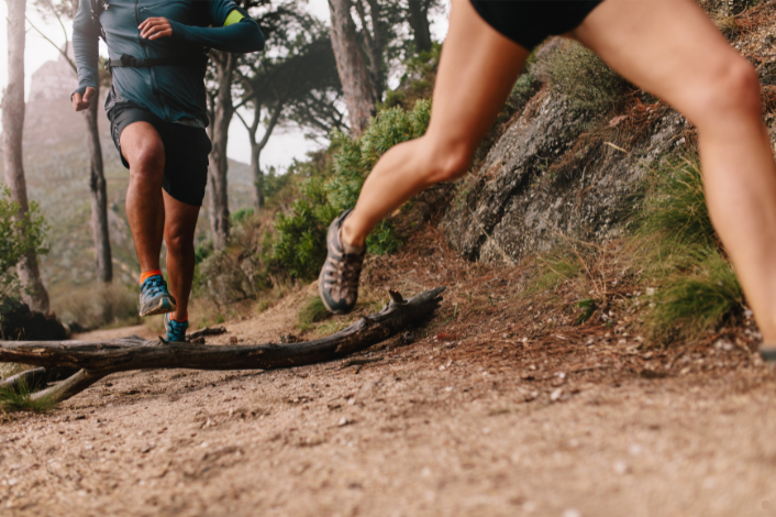 Two people running along a wooded trail