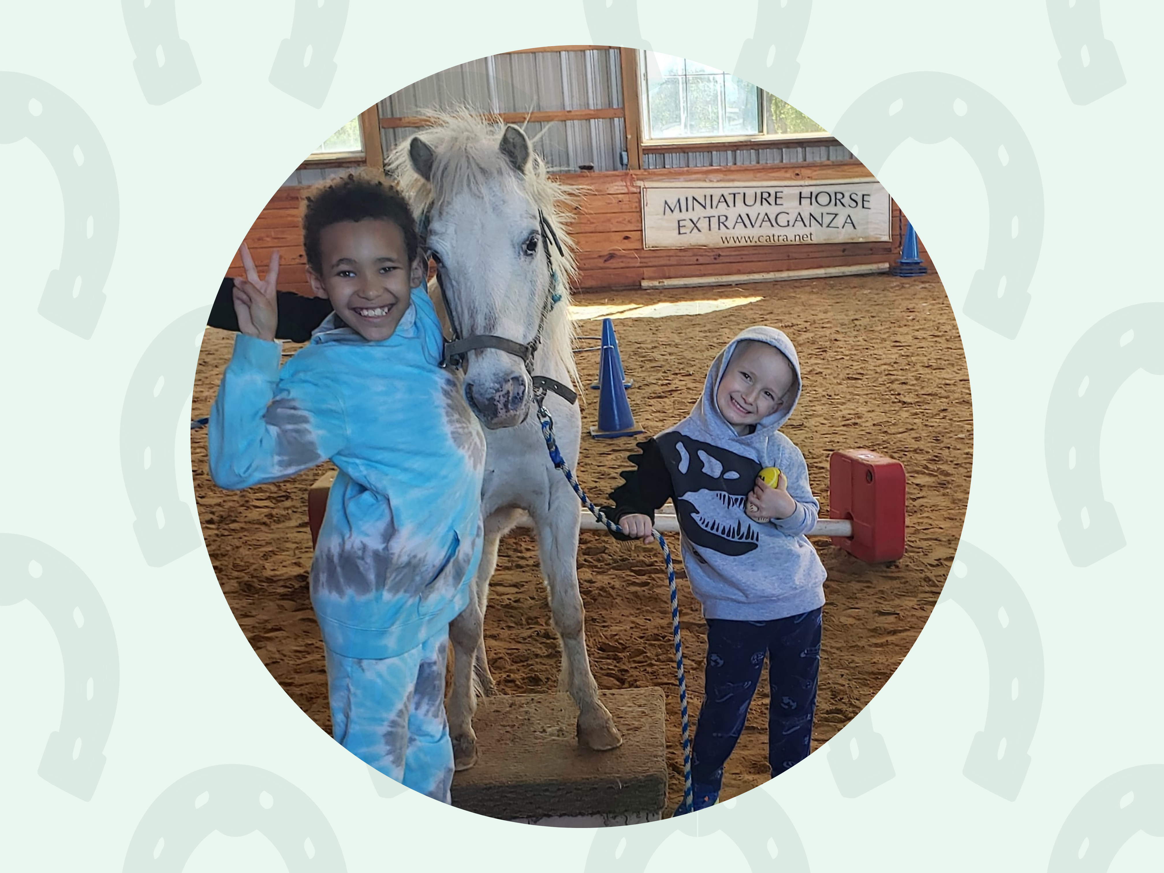 Child smiling while standing beside a miniature horse.