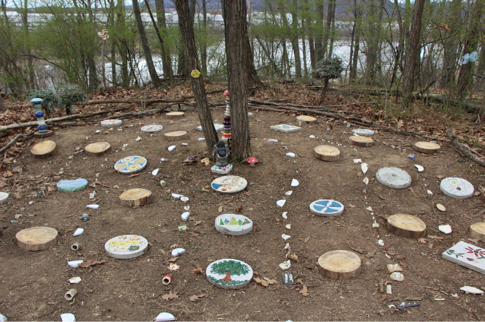 Art in the Wild Exhibit 2025_ Trees with stepping stones made of wood and painted stone.