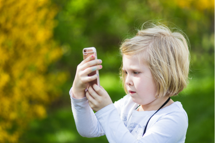 A young girl taking photos with a camera phone