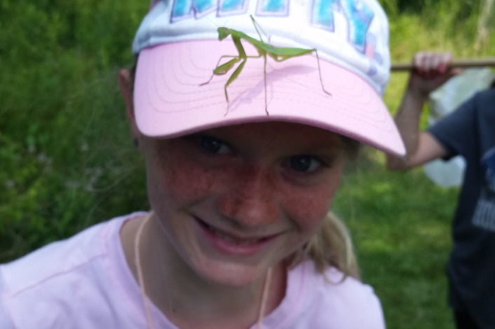 Young child with a praying mantis on hat