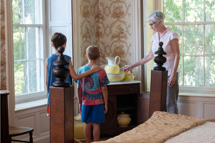 Two children and a tour guide describing a antique vase