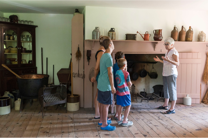 Family observing the mansion while tour guide speaks