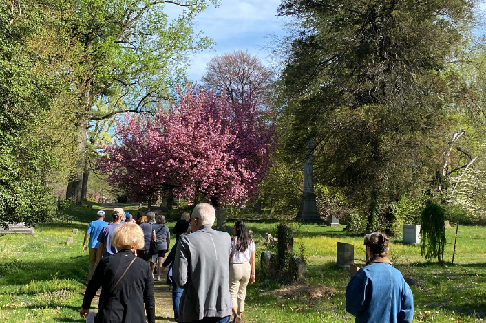 Group of people strolling through a cemetery with trees