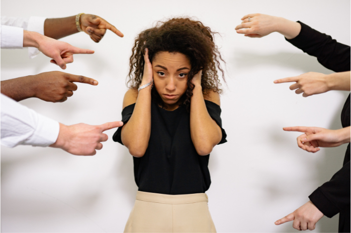 Person covering ears while being pointed at
