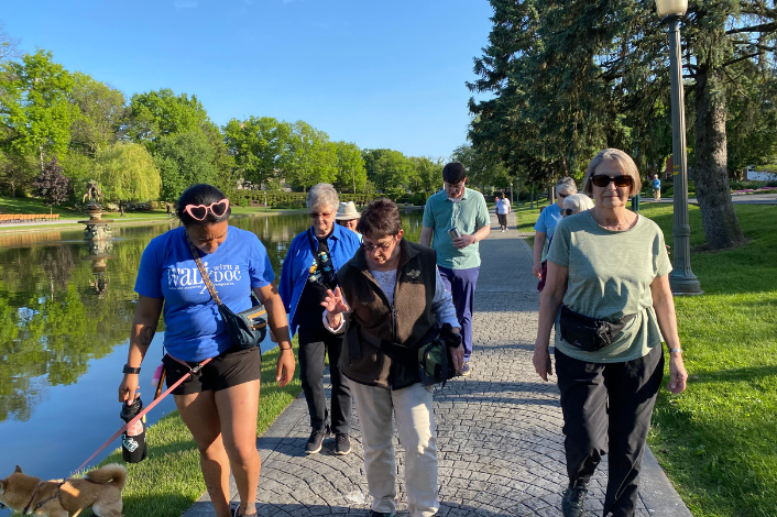 A group of walkers waling on a walkway around a lake