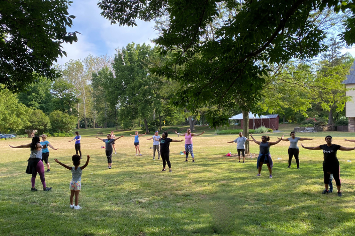 A group of people dancing outside on grass