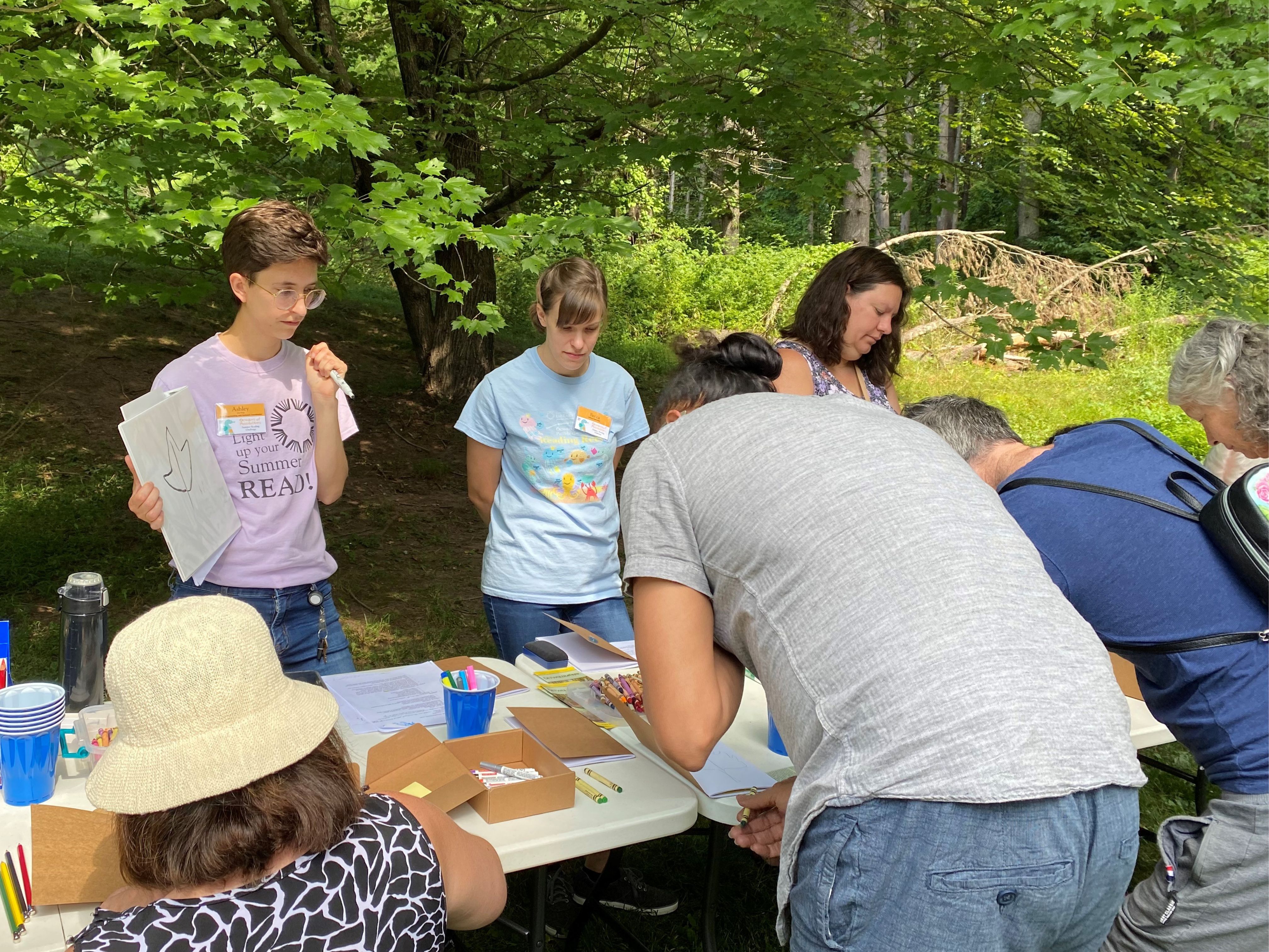 Dauphin County Library Staff overseeing a nature journaling program with participants in a wooded area