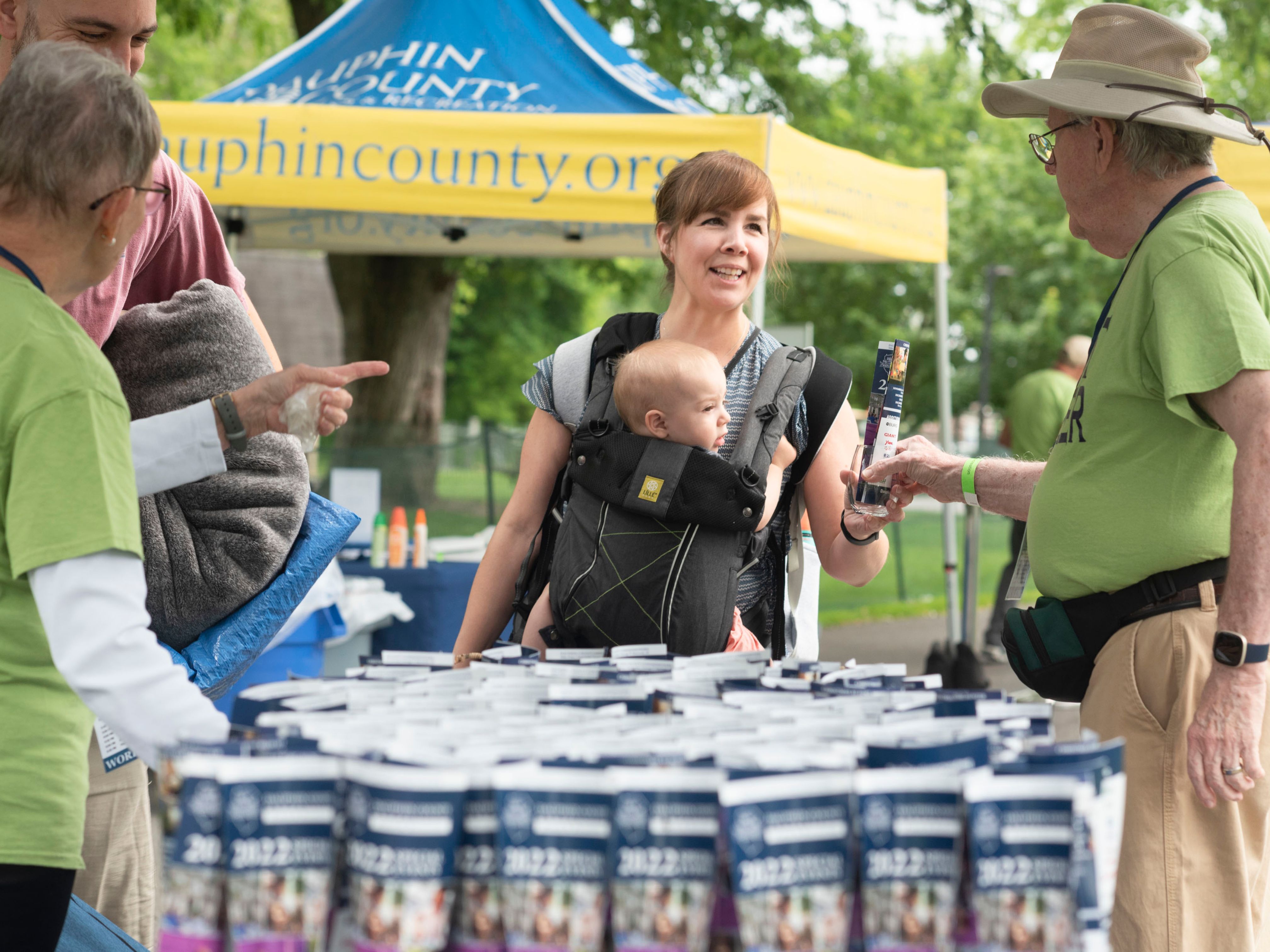 Volunteer handing a glass and brochure to a woman holding a baby