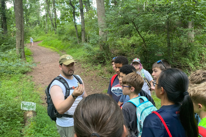 Person talking to children outside on a trail