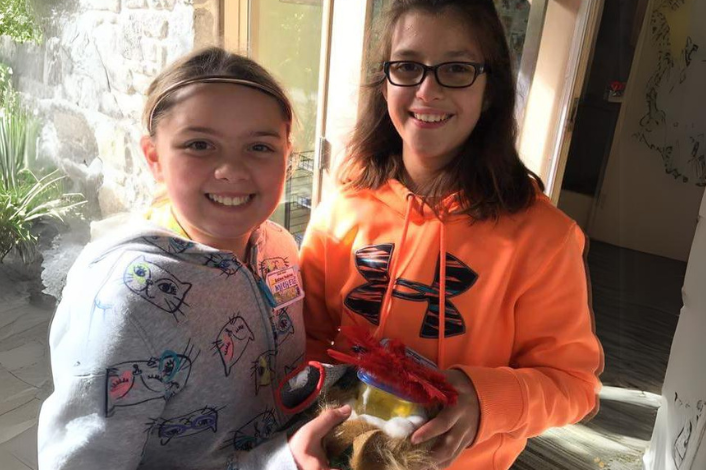 2 girls holding their crafted animal habitat